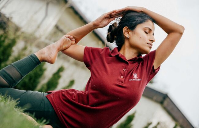 Eine indische Yoga Expertin macht Dehnübungen auf einer Wiese