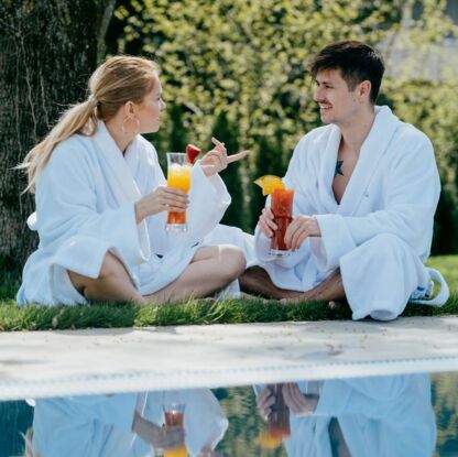 Zwei Personen im bademantel genießen einen Drink am Sole-Pool